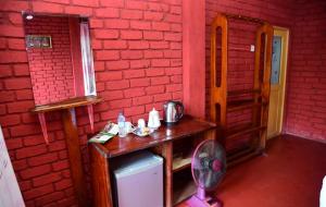 a room with a red brick wall with a wooden table at Rokky Hill Cottage Ella in Ella