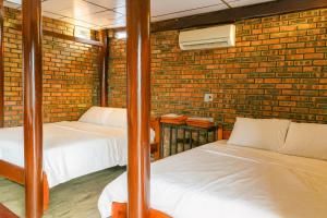 two beds in a room with a brick wall at Củi Homestay Huế in Hue