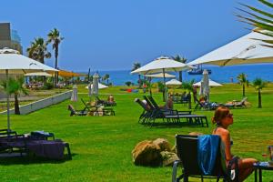 a group of people sitting in lawn chairs and umbrellas at Amphora Hotel & Suites in Paphos