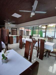 a restaurant with white tables and chairs and windows at Hostal Boutique Isabel in Managua