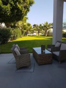 a patio with wicker chairs and a table with a lawn at Amphora Hotel & Suites in Paphos