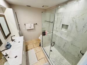een badkamer met een glazen douche en een wastafel bij Beachfront HouseSteps to Sand Sunset in Indian Rocks Beach