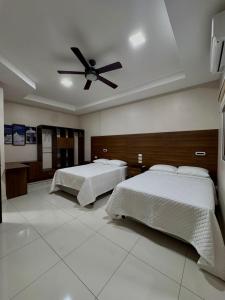 a bedroom with two beds and a ceiling fan at Hostal Boutique Isabel in Managua