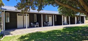 The Barracks at Brigadoon Village في بيتيس باي: منزل أسود أمامه كراسي وطاولات