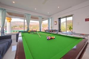 Villa With Turf & Indoor Games في Malavli: طاولة بلياردو في غرفة المعيشة مع طاولة بلياردو