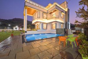 Villa With Turf & Indoor Games في Malavli: منزل به مسبح وطاولة وكراسي