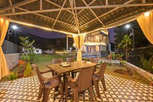 Villa With Turf & Indoor Games في Malavli: منطقة لتناول الطعام في الهواء الطلق مع طاولة وكراسي خشبية