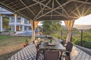 Villa With Turf & Indoor Games في Malavli: فناء مع طاولة وكراسي تحت مظلة