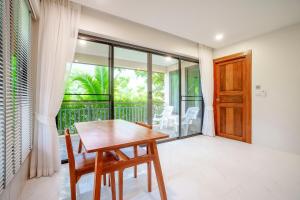 A103 Banjong 1 Bed apart, Near Nai Harn Beach في Ban Saiyuan (1): طاولة وكراسي خشبية في غرفة مع شرفة