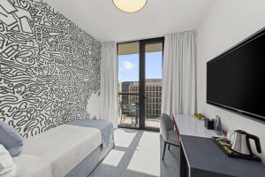 a bedroom with a bed and a tv and a desk at Nest Hotel, Aljada in Sharjah