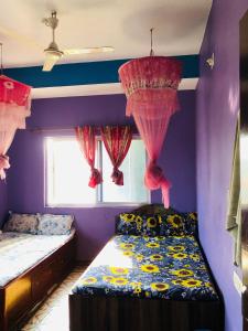 BirtamodUmananda Hotel and Lodge的一间卧室设有紫色的墙壁和一张带窗帘的床 更多18张照片