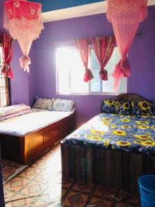 two beds in a bedroom with purple walls and a window at Umananda Hotel and Lodge in Birtamode
