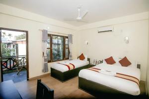 Un dormitorio con dos camas y un balcón. en Chitwan Mother Nature Resort, en Sauraha
