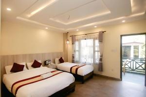 Una habitación de hotel con dos camas y balcón. en Chitwan Mother Nature Resort, en Sauraha