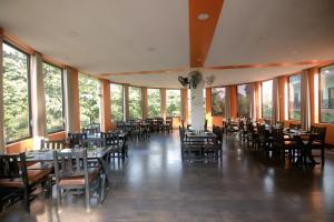 Un comedor con mesas y sillas y ventanas. en Chitwan Mother Nature Resort, en Sauraha