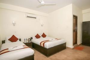 Dos camas en una habitación con paredes blancas. en Chitwan Mother Nature Resort, en Sauraha