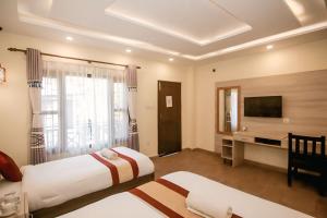 Una habitación de hotel con dos camas y un televisor. en Chitwan Mother Nature Resort, en Sauraha