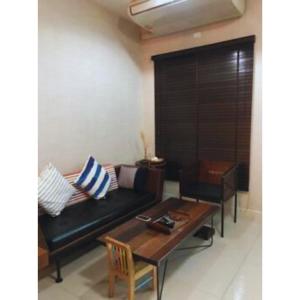 een woonkamer met een zwarte bank en een tafel bij Leon Sukhumvit 62 in Bangkok