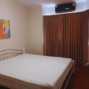 een slaapkamer met een bed en een televisie erboven. bij Leon Sukhumvit 62 in Bangkok