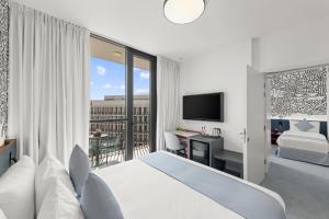 a bedroom with a bed and a balcony with a desk at Nest Hotel, Aljada in Sharjah