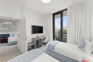 a hotel room with a bed and a desk and a tv at Nest Hotel, Aljada in Sharjah