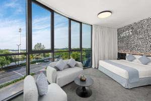 a bedroom with a bed and a couch and windows at Nest Hotel, Aljada in Sharjah