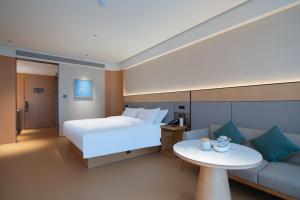 een hotelkamer met een bed en een bank bij JI Hotel Qingdao Laoshan MixC in Qingdao