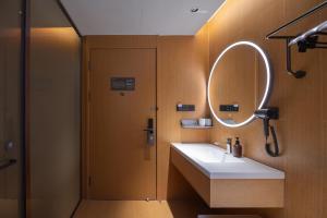 een badkamer met een wastafel en een spiegel en een douche bij JI Hotel Qingdao Laoshan MixC in Qingdao +27 foto's