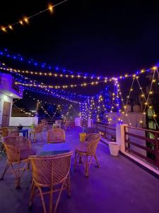 Un patio con mesas, sillas y luces. en Aradhya Gange Residency, en Rishīkesh