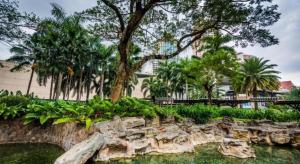 a park with a tree and a rock wall at F1 Hotel Manila in Manila