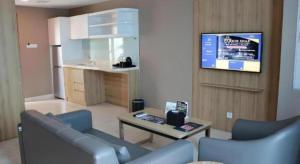 a living room with a couch and a tv on a wall at Wing Hotel Kualanamu Airport in Kampungbesar