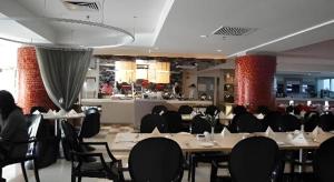Un comedor con mesas y sillas y un bar. en The CentrePoint Hotel, en Kampong Kiulap
