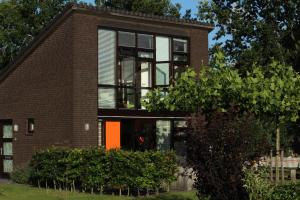 a brick house with an orange door at Bergen Holiday Home in Schoorl