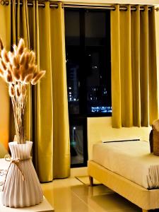 a bedroom with yellow curtains and a vase with flowers at BH UrbanSky Condo in Mactan