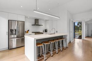 a kitchen with a white counter and bar with stools at White Sands Haven - Omaha Family Escape in Omaha
