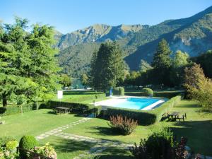 a garden with a swimming pool and mountains in the background at Appartamento Belvedere in Molina di Ledro