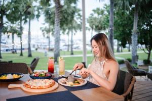 eine Frau, die mit einem Teller Essen an einem Tisch sitzt in der Unterkunft Ocean Marina Resort Pattaya Jomtien in Na Jomtien