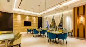 Jinjiang Inn Select Xixian New Distict Century Avenue في Xianyang: غرفة طعام بها طاولات وكراسي وتلفزيون