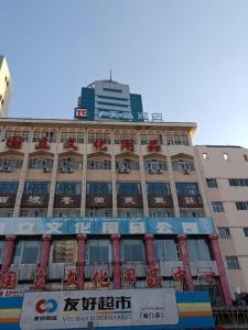 PAI Hotels·Urumqi South Gate Xinhua Bookstore في أورومكي: مبنى كبير مع لافتة أمامه