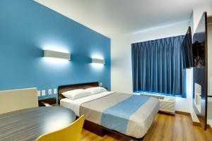 a bedroom with a bed and a blue wall at Motel 6 Poplar Bluff, MO in Poplar Bluff