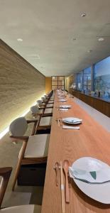 a long row of tables with white plates on them at 住 京都小川生薬 VILLA Jyu KyotoOgawaSyouyaku VILLA in Kyoto