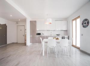 een witte keuken met een tafel en witte stoelen bij Appartamenti Ora e Peler in Riva del Garda