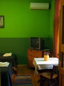 a green room with two beds and a tv at Guest Accommodation Etno Konak Tašana in Niš