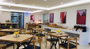 a restaurant with tables and chairs in a room at Borrman Hotel Zhanjiang Shimao Building High-speed Railway Station in Tchia-k'am