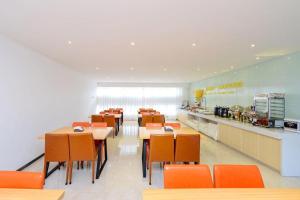 a dining room with tables and chairs and a kitchen at City Comfort Inn Guiyang Yan'an Middle Road Fountain Metro Station in Guiyang