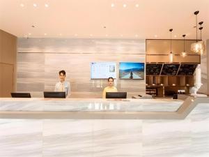 two people standing in a lobby with their laptops at City Comfort Inn Lingshui Central Avenue Bus Station in Lingshui