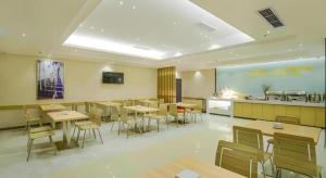 a restaurant with tables and chairs and a kitchen at City Comfort Inn Dujiangyan Municipal Government in Dujiangyan