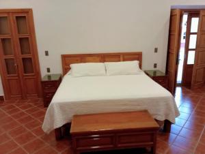 a bedroom with a white bed and wooden furniture at Casa Purépecha, Habitación Itzi in Morelia