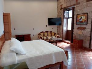 ein Schlafzimmer mit einem Bett und ein Wohnzimmer mit einem Fernseher in der Unterkunft Casa Purépecha, Habitación Itzi in Morelia