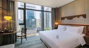 um quarto com uma grande cama branca e uma grande janela em Shenzhen Apex Hotel (Technology Park Branch) em Shenzhen